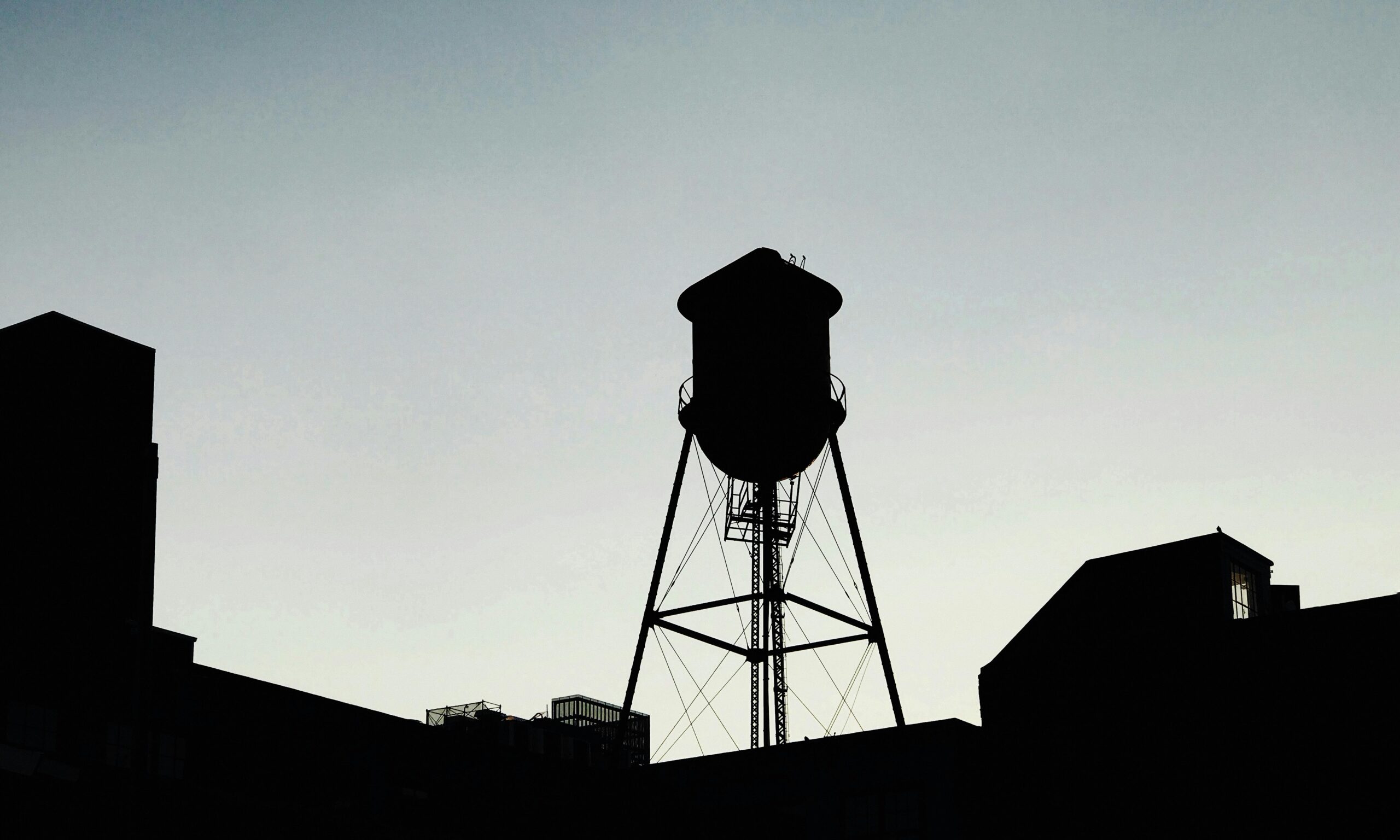 A striking silhouette of a water tower against the evening sky in Brooklyn, NY.